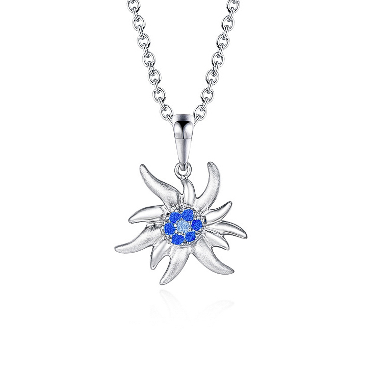 Pendentif Edelweiss Magellan Argent. Collier Edelweiss avec des zircons bleus clairs et bleus foncés modèle by White Alpina. Bijoux pour hommes et femmes. En outre, ce magnifique bijou est livré dans un écrin avec une chaîne en acier inoxydable. De plus, White Alpina propose ce pendentif en argent 925 avec une variation entre le mâte et le brillant.